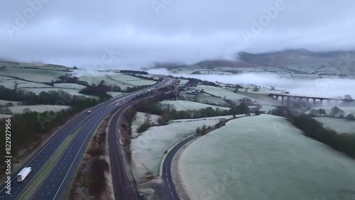 Light traffic on M6 motorway with low cloud cover on hills on frosty winter morning and stone viaduct backed by mist and fog. Tebay, English Lake District, Cumbria, UK. photo