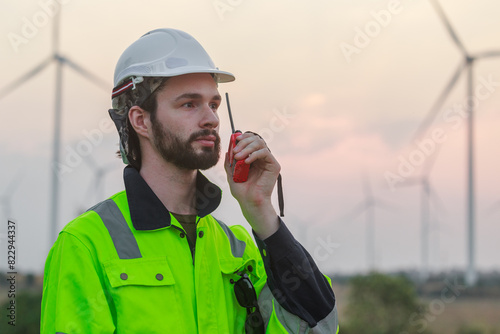 Engineer wearing safety uniform using talkie walkie discussed plan about renewable energy at station energy power wind. technology protect environment reduce global warming problems.