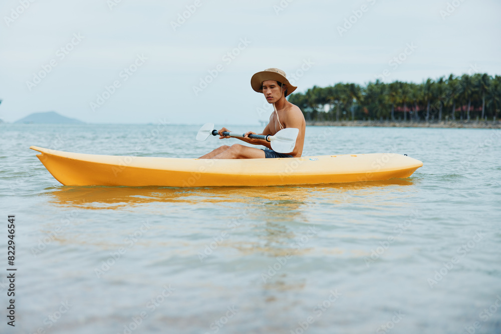 Happy Asian Man Enjoying Kayaking Adventure on Tropical Beach