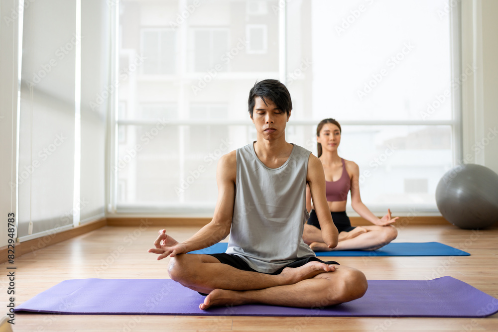 Asian young amputee without arm doing yoga with trainer in fitness gym. Asian young amputee without arm doing yoga with trainer in fitness gym.
