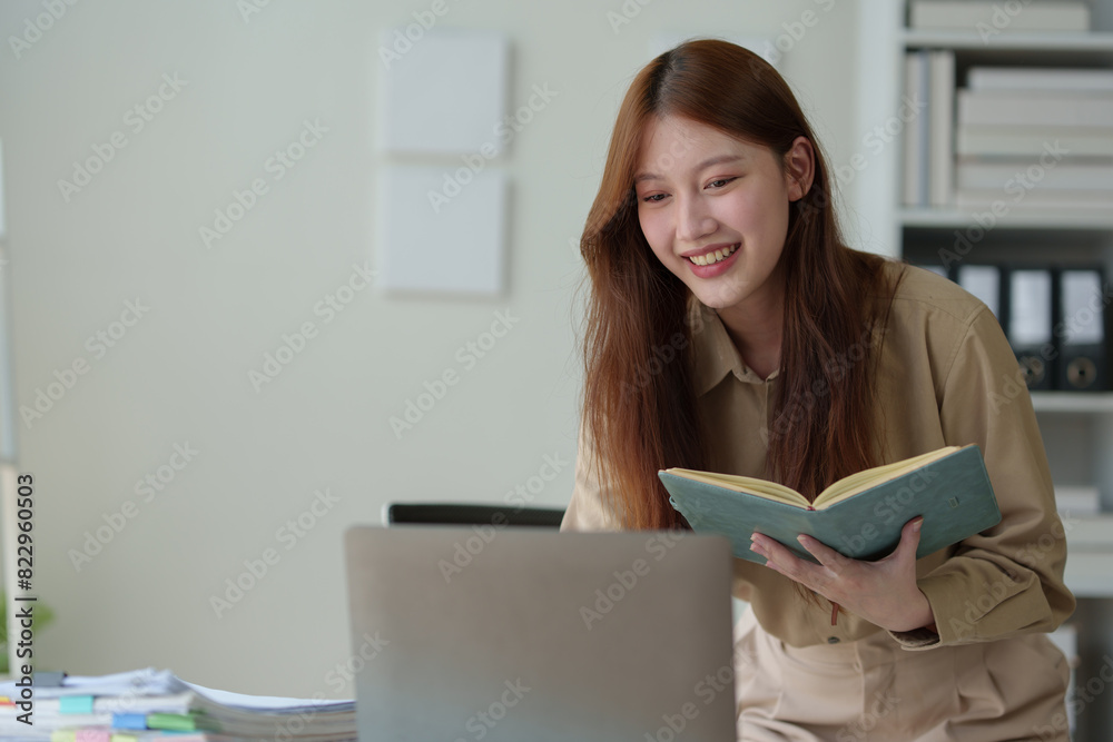 Young woman working on laptop in office Asian businesswoman sitting and taking notes in a notebook Thinking of ideas at your desk Beautiful independent woman working online with paperwork. Young woman working on laptop in office Asian businesswoman sitting and taking notes in a notebook Thinking of ideas at your desk Beautiful independent woman working online with paperwork.