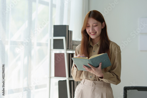 Young woman working on laptop in office Asian businesswoman sitting and taking notes in a notebook Thinking of ideas at your desk Beautiful independent woman working online with paperwork.