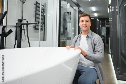 Man customer choosing ceramic bath in bathroom furniture store © Serhii