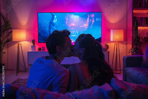 A couple is kissing in front of a television