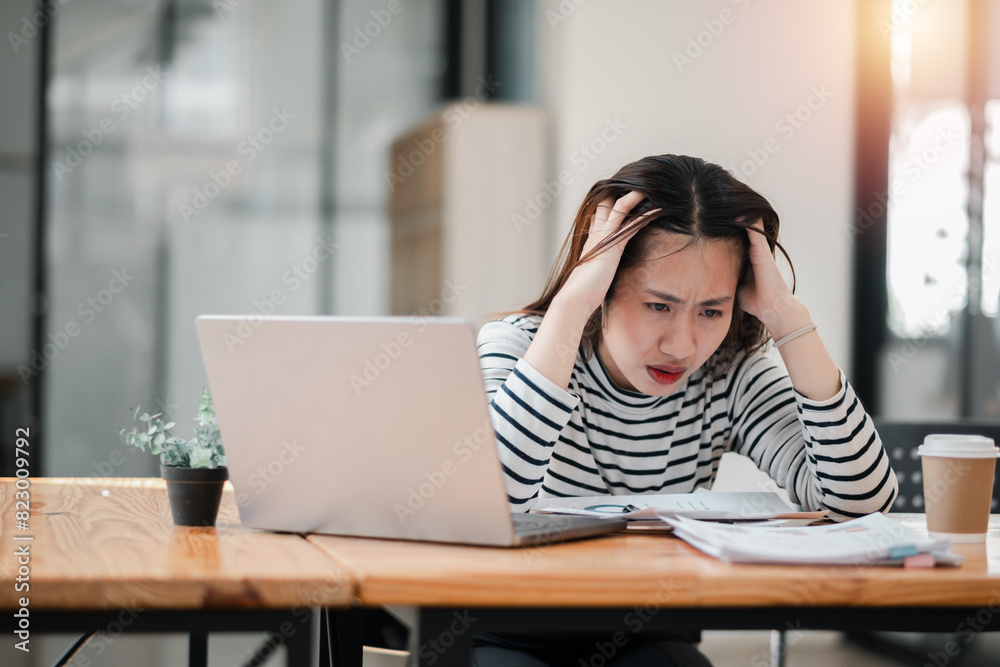A woman is sitting at a desk with a laptop and a cup of coffee. She is looking at the laptop with a worried expression on her face A woman is sitting at a desk with a laptop and a cup of coffee. She is looking at the laptop with a worried expression on her face