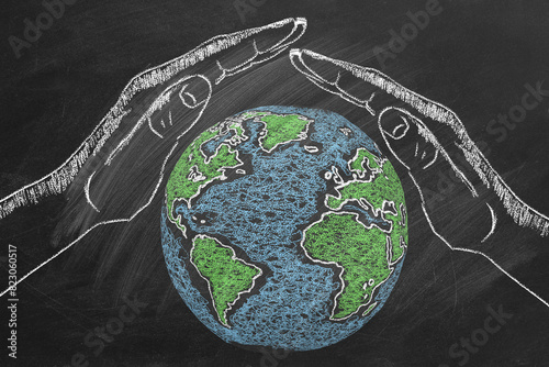 Chalk-drawn hands cover encircle the Earth on a blackboard, emphasizing the importance of protecting our planet and promoting environmental conservation. Save Our Planet Concept