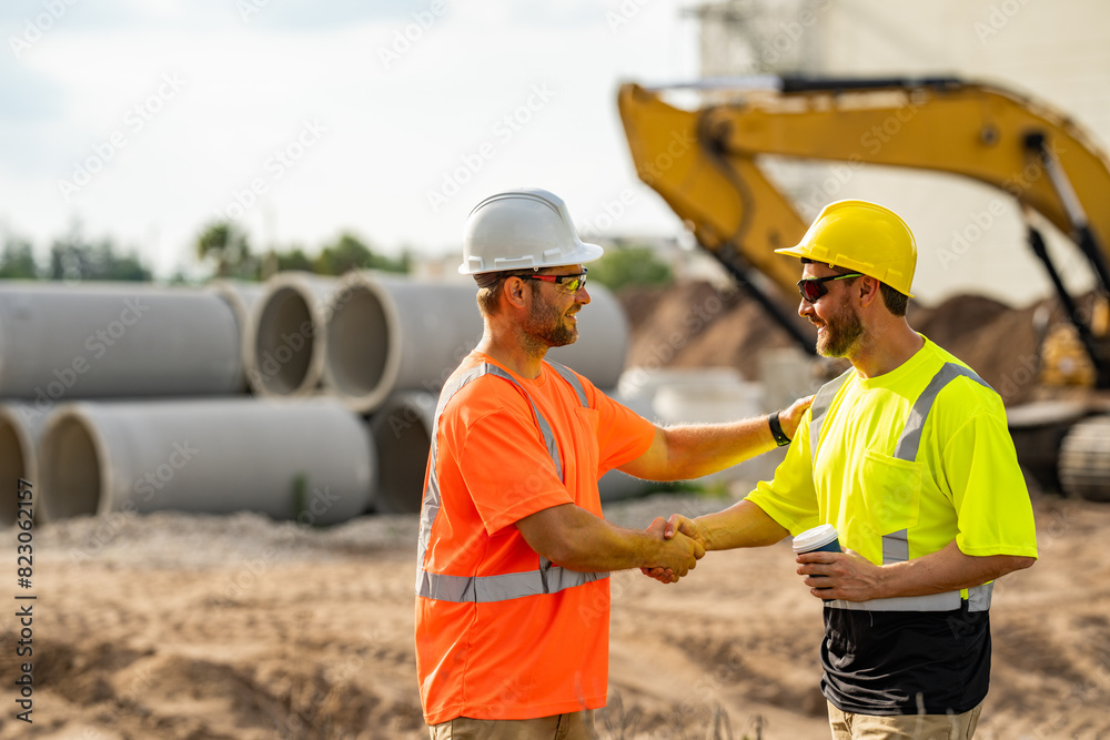 Two construction site workers in helmet work outdoors. Builders workers working on construction site. The job of a construction site worker requires a lot of physical strength. Two construction site workers in helmet work outdoors. Builders workers working on construction site. The job of a construction site worker requires a lot of physical strength.