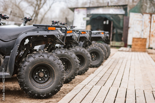 Row of quad bikes parked outside rental service, closeup photo. Outdoor adventure: Several quad bikes parked, perfect for exploring rugged terrain
