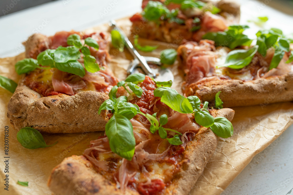 Whole wheat pizza with italian raw ham, mozzarella cheese and basil leaves Whole wheat pizza with italian raw ham, mozzarella cheese and basil leaves