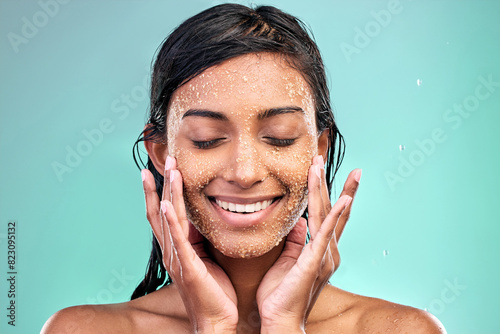 Woman face, beauty and salt scrub in studio with water drops for skin care, hygiene and dermatology. Model eyes closed thinking of facial exfoliation or makeup removal with texture on blue background photo