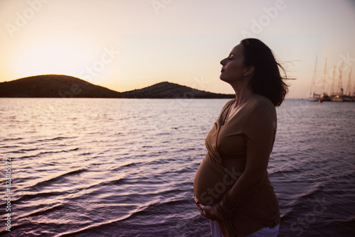 Pregnant woman on the shore of a lagoon at sunset. The breeze comforts her © Miriam