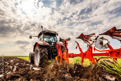 Powerful tractor turns the soil, readying the field for planting under a dramatic sky