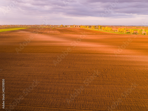 Aerial shot of a farmer seeding  sowing crops at field. Sowing is the process of planting seeds in the ground as part of the early spring time agricultural activities.