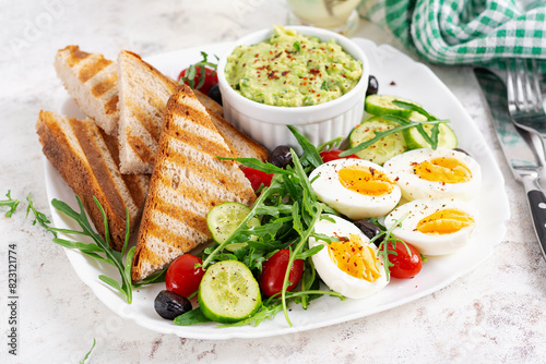 Healthy breakfast. Boiled egg, guacamole, toast and fresh salad.