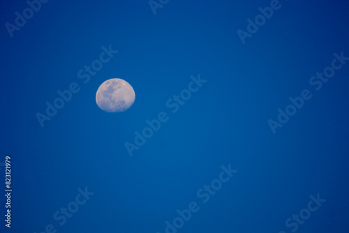 Growing moon in the blue sky. Half of the moon s disk in the evening blue sky.