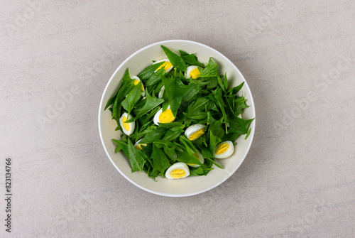salad of fresh green spinach leaves and boiled quail eggs in a grey plate on a gray background top view