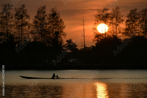 Sailing boat silhouette in a lake with sunset in backgrounก