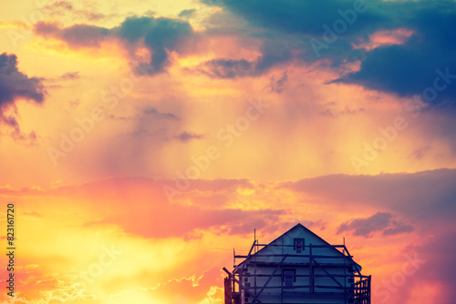 Rural landscape with a beautiful gradient evening sky at sunset. Silhouette of a house under construction against the sky