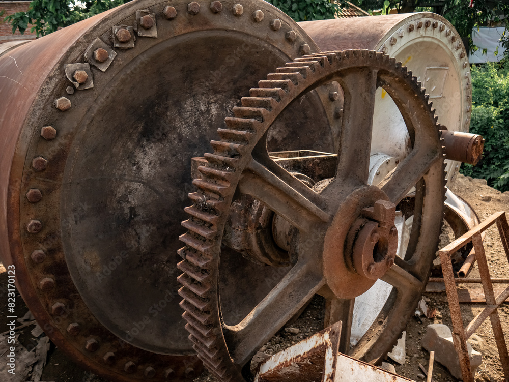 a large, old, rusty gear mounted on a worn out machine