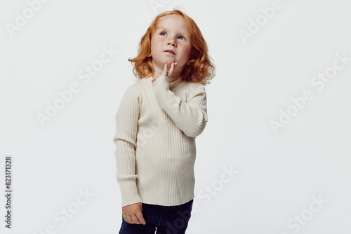 Young girl contemplating against clean white background in stylish outfit for fashion photo shoot