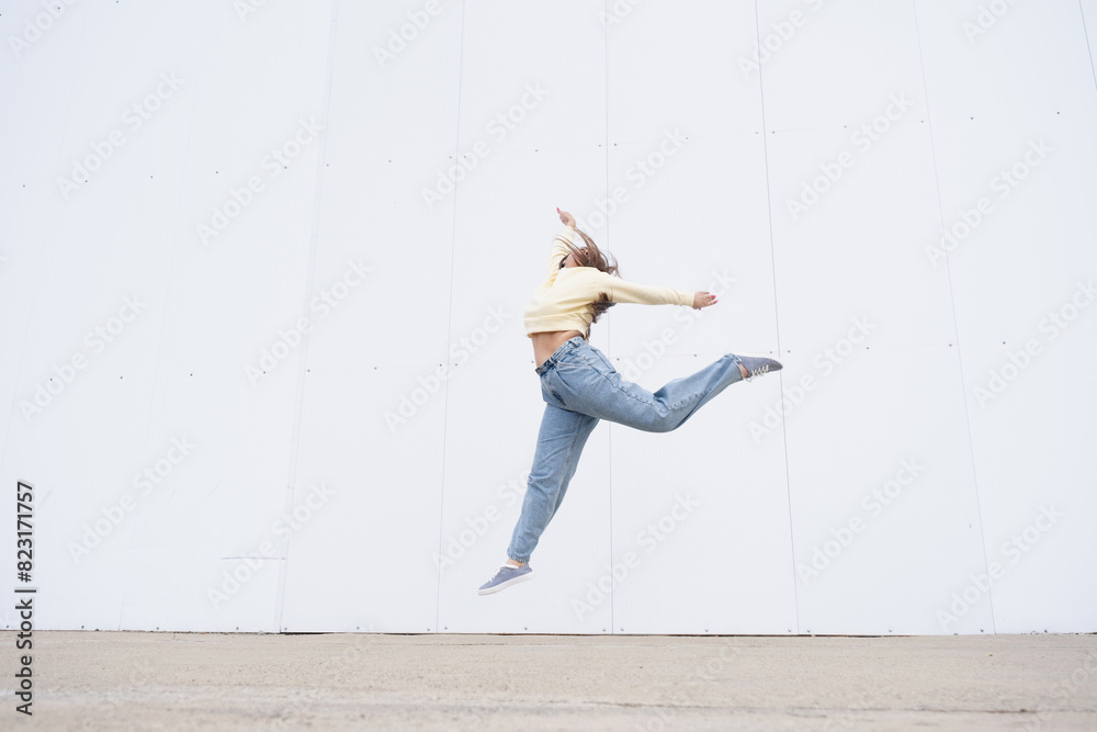 plus size woman wearing casual clothes dancing on white wall background in the street