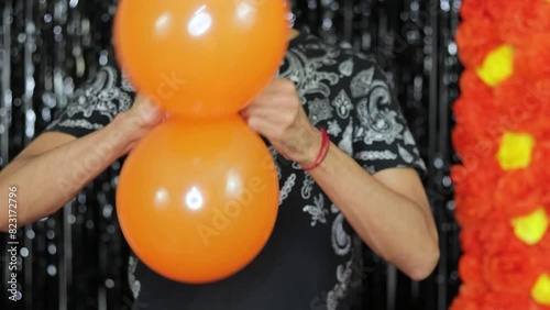 Tying together two inflated orange balloons for Halloween decoration. photo