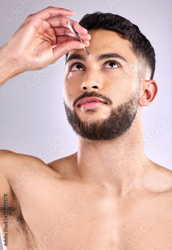 Face, self care and tweezers with a man model plucking eyebrows in studio background, hair removal or trim. Skincare, wellness and beauty routine for grooming, hygiene and cosmetics for cleaning skin