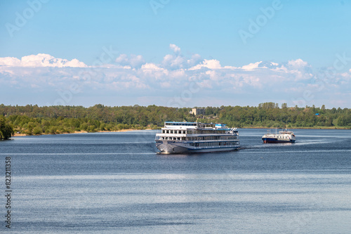 A cruise ship and a tanker tug move along the river.