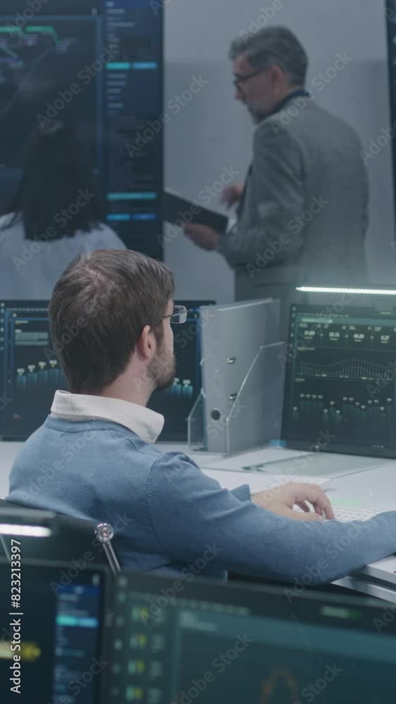 Technical support specialists sit at computers with displayed blockchain network map and server data. Big data scientists work in monitoring room. Big screens on the wall. Concept of cyber security. Technical support specialists sit at computers with displayed blockchain network map and server data. Big data scientists work in monitoring room. Big screens on the wall. Concept of cyber security.