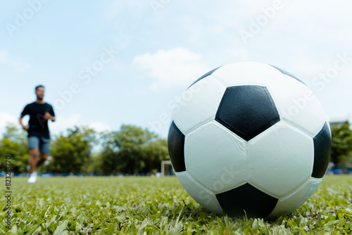 Soccer ball on the grass and football player exercising