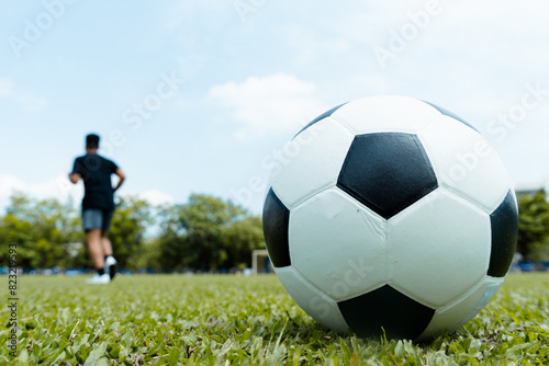Soccer ball on the grass and football player exercising