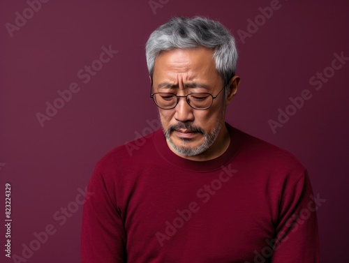 Maroon background sad Asian man. Portrait of older mid-aged person beautiful bad mood expression boy Isolated on Background depression anxiety fear burn out health issue © Zickert