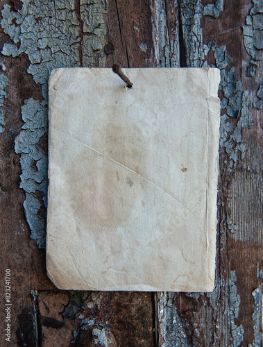 Old paper advertisement hanging on aged wall nailed by rusty doornail photo