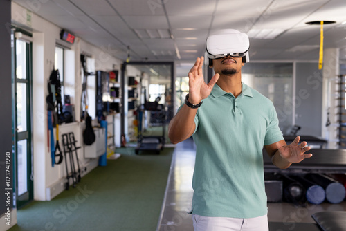 Biracial male physical therapist wearing virtual reality headset at gym rehabilitation center, navig photo