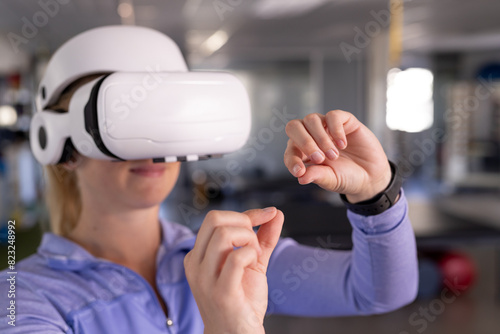 Caucasian female therapist in VR headset gestures at gym rehabilitation center photo