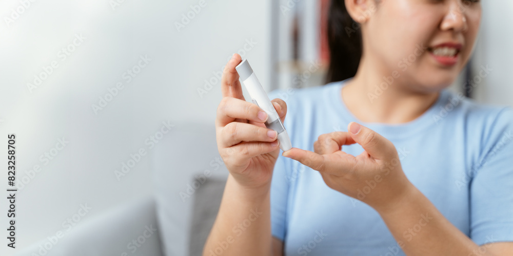 Asian woman using lancet on finger for checking blood sugar level by Glucose meter Asian woman using lancet on finger for checking blood sugar level by Glucose meter