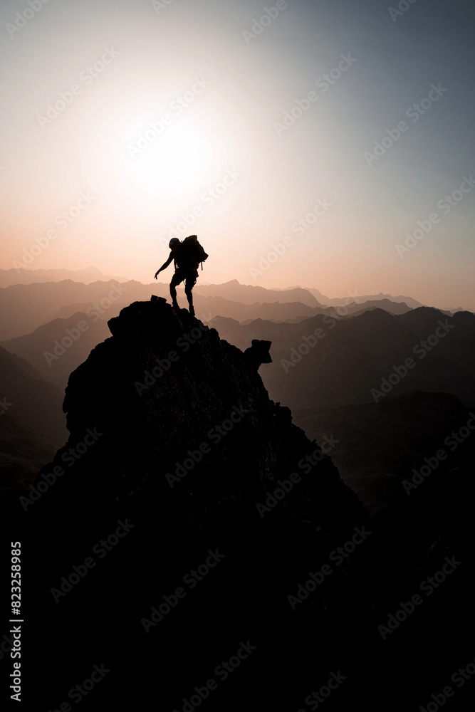 Fototapeta premium Silhouette of 2 mountaineers climbing and reaching a sharp pinnacle in the French Pyrenees