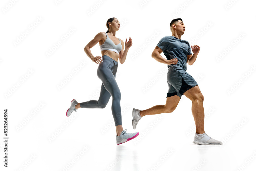 Two athletes sprinting, captured in moment of peak effort against white studio background. Synchronized movement. Concept of people in sport, healthy lifestyle, teamwork, motivation. Ad Two athletes sprinting, captured in moment of peak effort against white studio background. Synchronized movement. Concept of people in sport, healthy lifestyle, teamwork, motivation. Ad