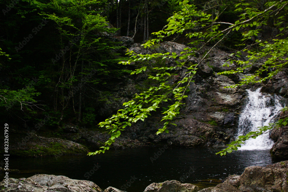 Scenic Memel Falls in New Brunswick cascading through lush forest with rocks and green foliage Scenic Memel Falls in New Brunswick cascading through lush forest with rocks and green foliage
