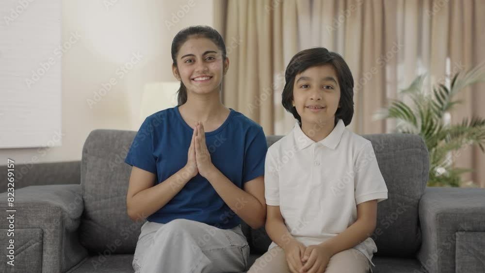Happy Indian siblings doing Namaste to the camera Happy Indian siblings doing Namaste to the camera