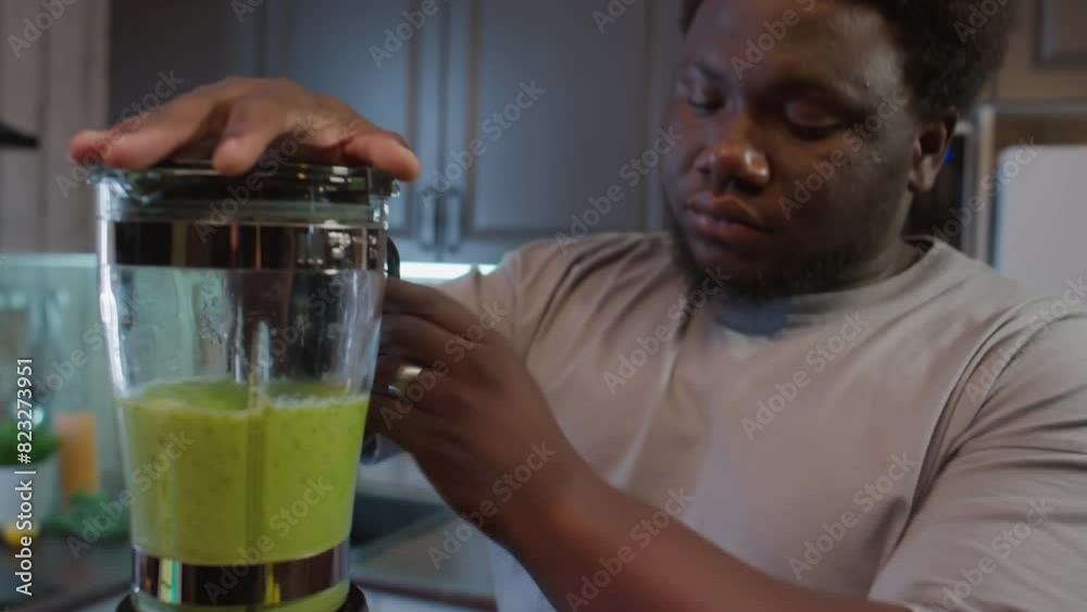 Black man with overweight preparing healthy smoothie drink in kitchen blender at home while following diet Black man with overweight preparing healthy smoothie drink in kitchen blender at home while following diet