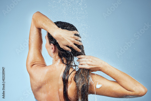 Back, shampoo and woman with hair care for wellness, shower and soap on blue background for washing.Clean, female person and water on studio backdrop for beauty, hygiene and cleaning in morning