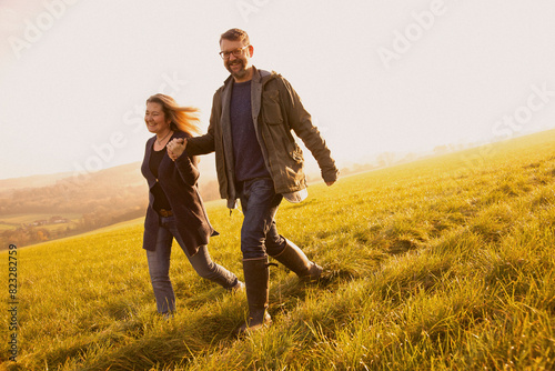 Smiling Couple Walking in a Field Holding Hands
 photo