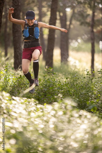 A woman is running through a forest with her arms outstretched