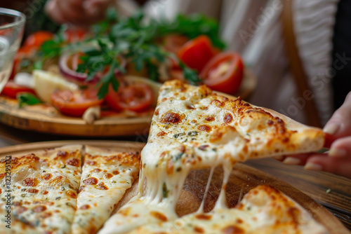 Woman taking a piece of delicious cheese pizza at a wooden table 