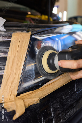 Person using a machine to polish automotive lighting on a car headlight