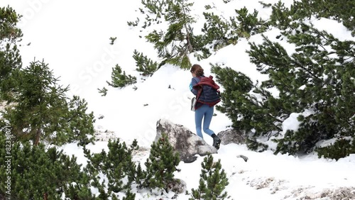 Confident Mid adult Caucasian Woman Hiker ascending on A Mountain Path in Hiking Boots in early winter season with Snow photo