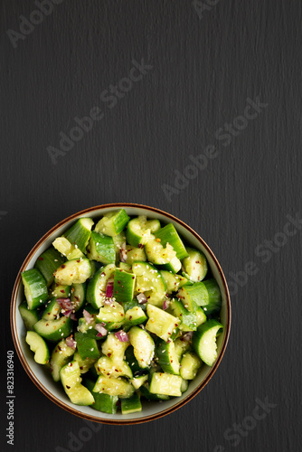 Homemade Smashed Cucumber Salad in a Bowl on a black background, top view. Space for text.