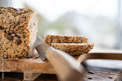 Freshly sliced multigrain bread on wooden cutting board with kniffe. Close-up with short depth of field in front of bright window.