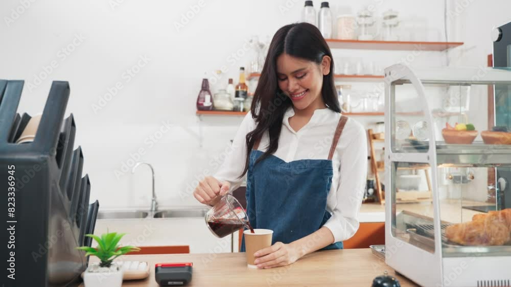 Young Asian woman barista pouring coffee into a take away cup for customer in cafe shop, Bakery and coffee small business owner concept Young Asian woman barista pouring coffee into a take away cup for customer in cafe shop, Bakery and coffee small business owner concept